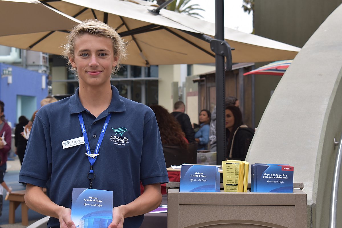 Teenager poses with a visitor guide outside the Aquarium.